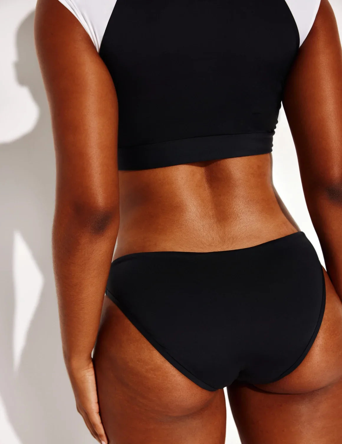 Back view of model wearing the Leakproof Sculpt Bikini Swim Bottom highlighting the coverage and fit – Black – view 8 of 14