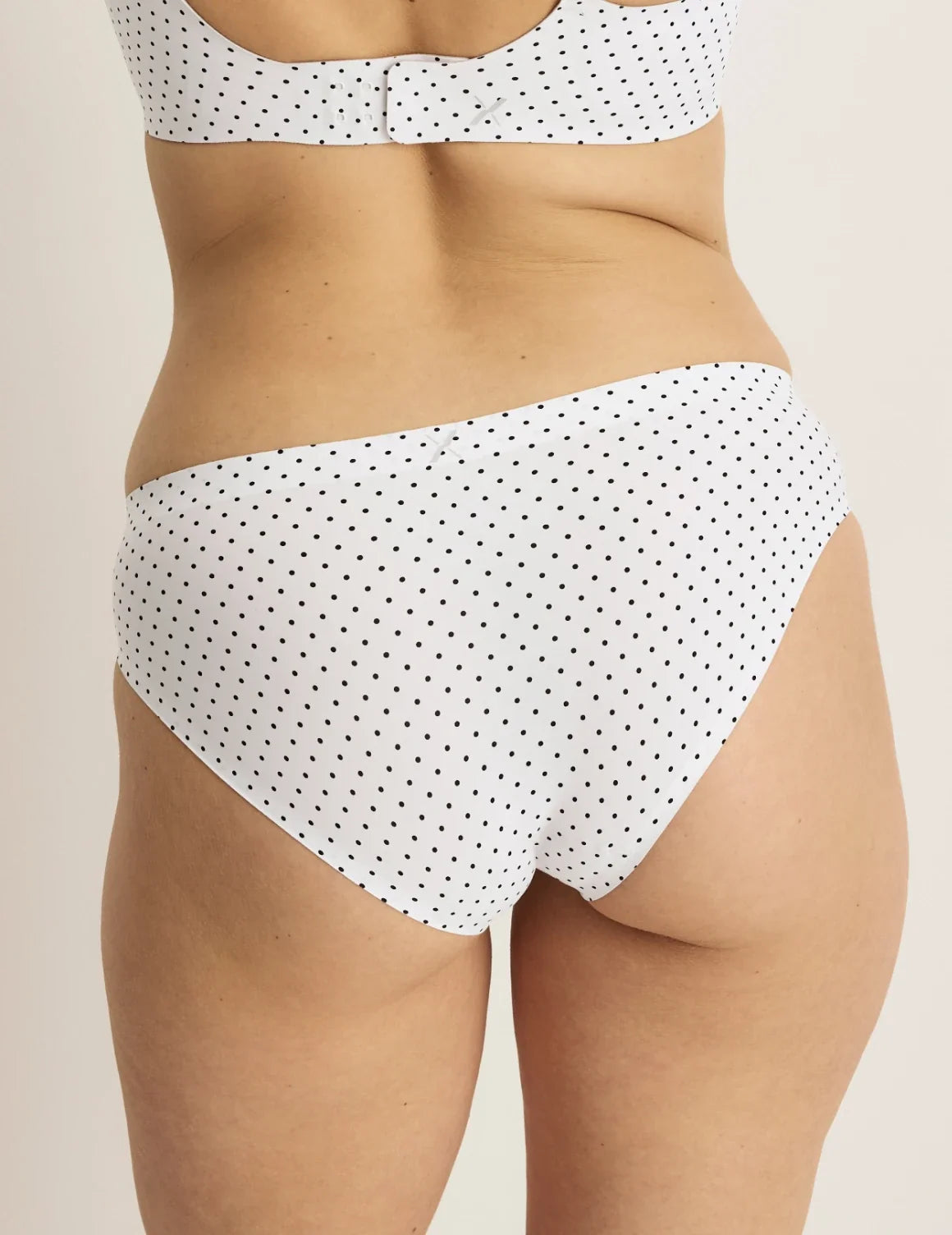 Back view of model wearing the Essential No-Show Bikini highlighting the coverage and smooth fit – White with Black Polka Dot – view 8 of 31