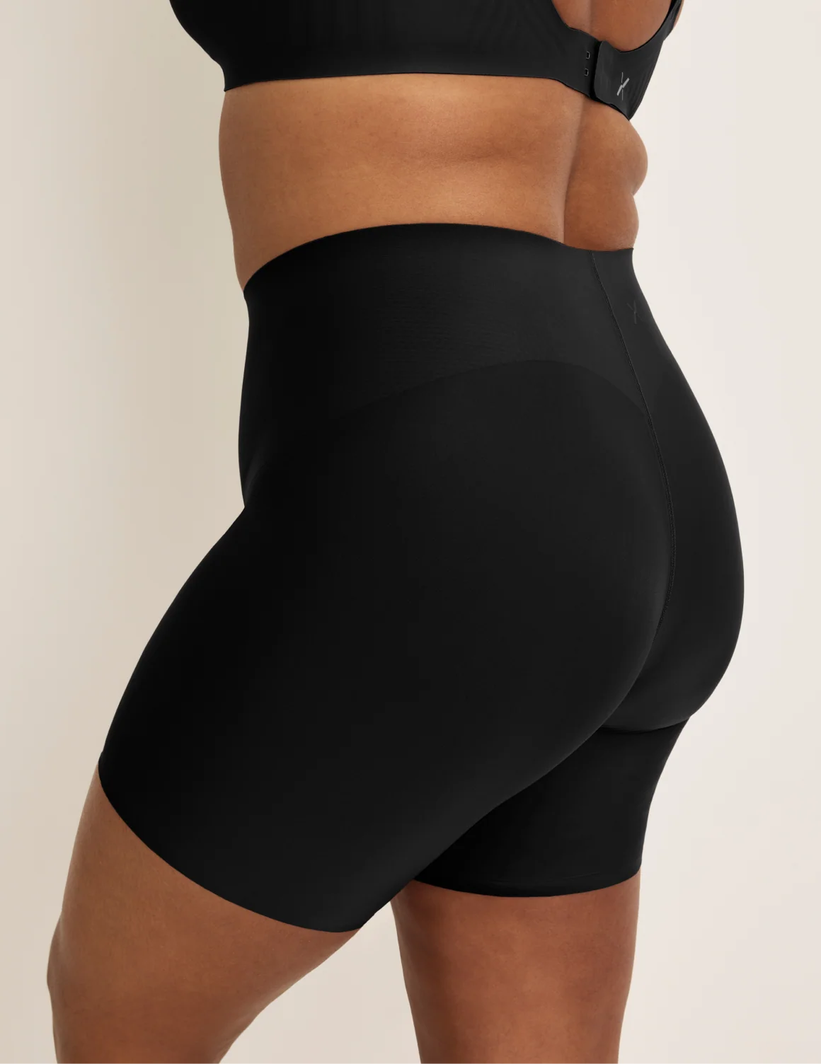 Side view of model wearing the Leakproof Contour Thigh Saver® 6”, highlighting the coverage and smooth fit – Black – view 6 of 19
