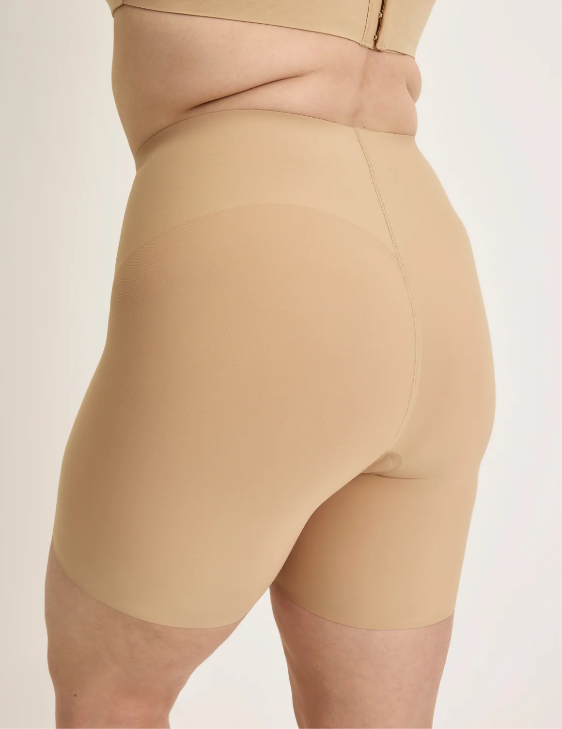 Side view of model wearing the Leakproof Contour Thigh Saver® 6”, highlighting the coverage and smooth fit – Warm Sand – view 12 of 19