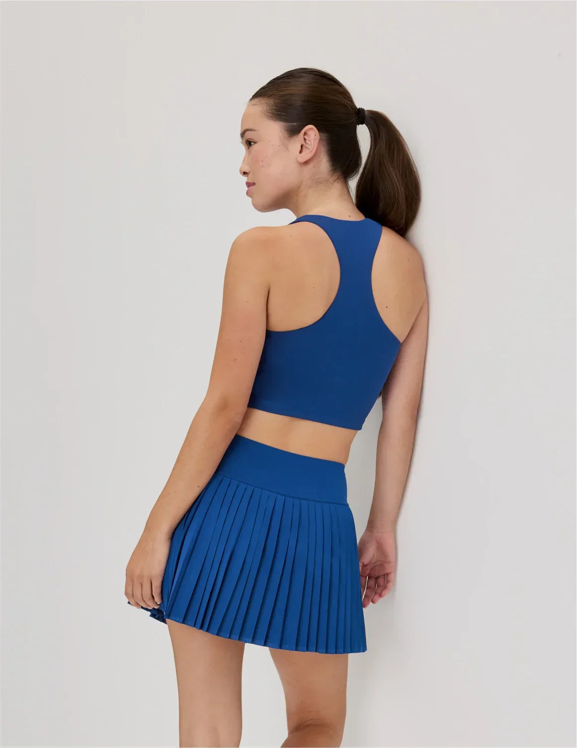 Back view of model wearing the Teen First Serve Pleated Skort highlighting the coverage and fit – Shady Blue – view 5 of 11