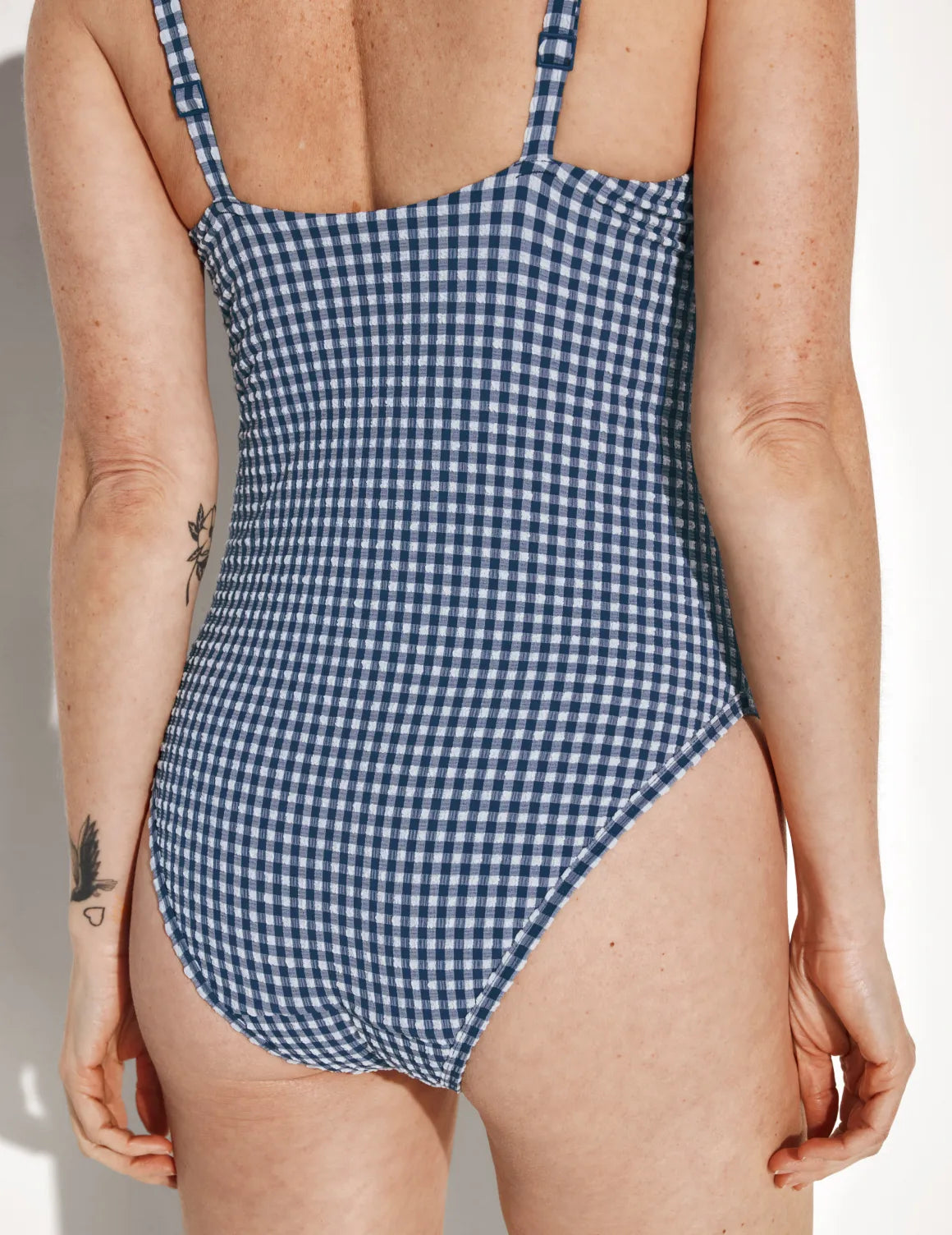 Back view of model wearing the Leakproof Seersucker Sculpt Deep V One Piece Swimsuit highlighting the neckline, coverage and fit – Navy Seersucker – view 4 of 6