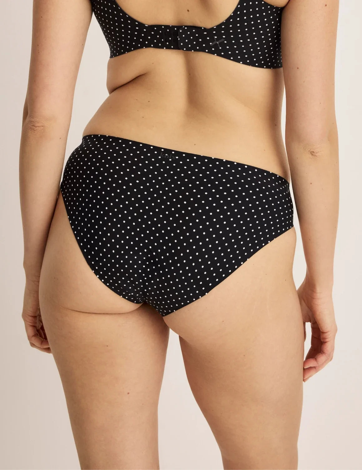 Back view of model wearing the Leakproof UltraThin No-Show Bikini highlighting the coverage and smooth fit – Black with White Polka Dot – view 3 of 47