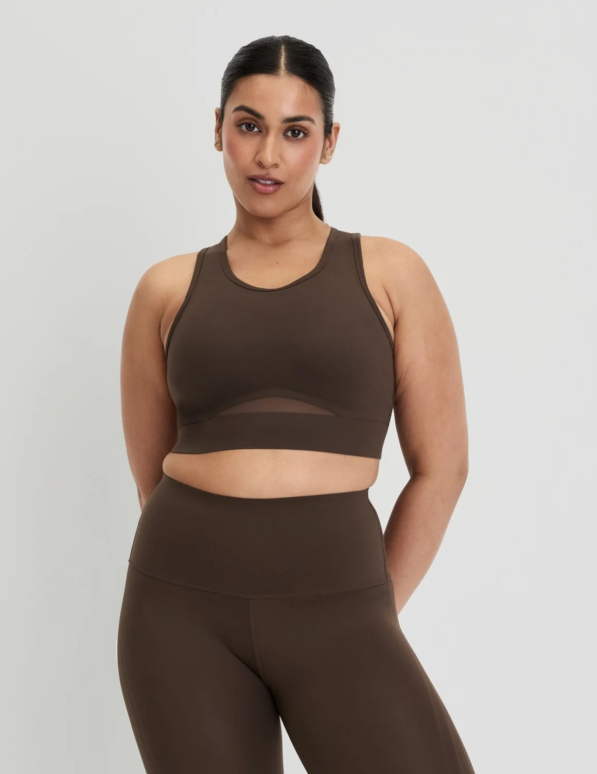Front view of model wearing the Momenta Racerback Sports Bra, highlighting the neckline, strap design, and silhouette – Espresso – view 5 of 21