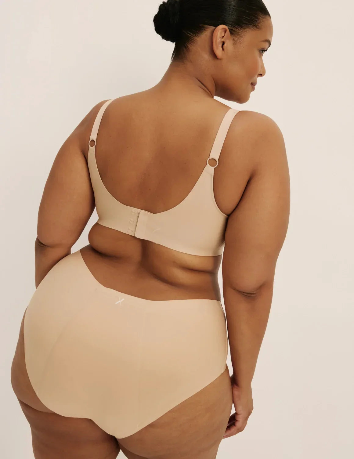 Back view of model wearing the Revolution Nursing Bra, highlighting the neckline, nursing clip strap design, and smooth silhouette β Warm Sand β view 6 of 21