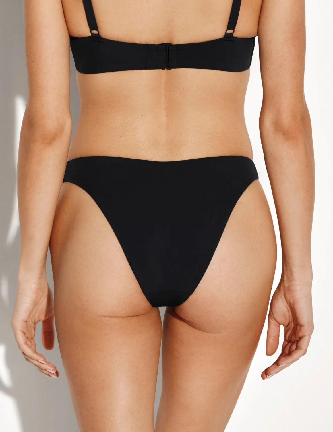 Back view of model wearing the Sculpt Dipped Bikini Swim Bottom highlighting the coverage and fit – Black – view 4 of 8