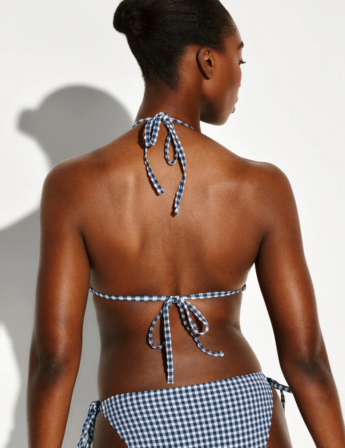 Back view of model wearing the Seersucker Sculpt Triangle Bikini Top, highlighting the neckline, strap design, and silhouette – Navy Seersucker – view 3 of 5