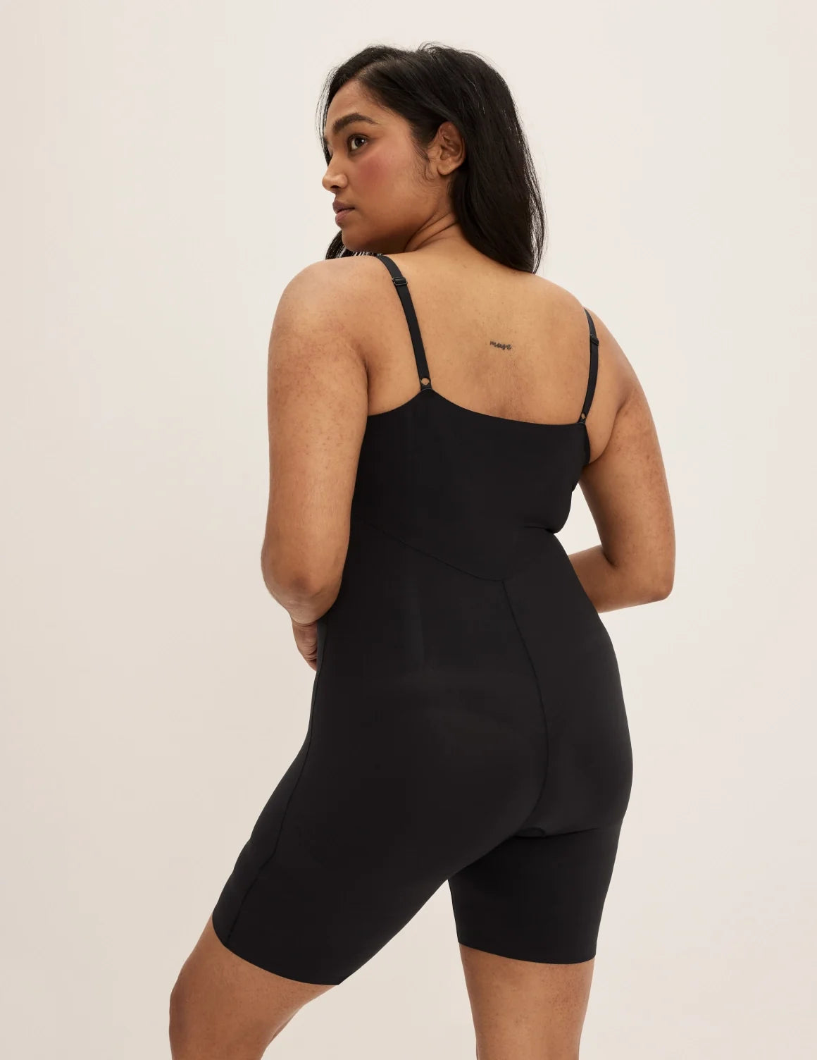 Back view of model wearing the Customizable Shaper Mid-Thigh Bodysuit highlighting the coverage and smooth fit – Black – view 3 of 11