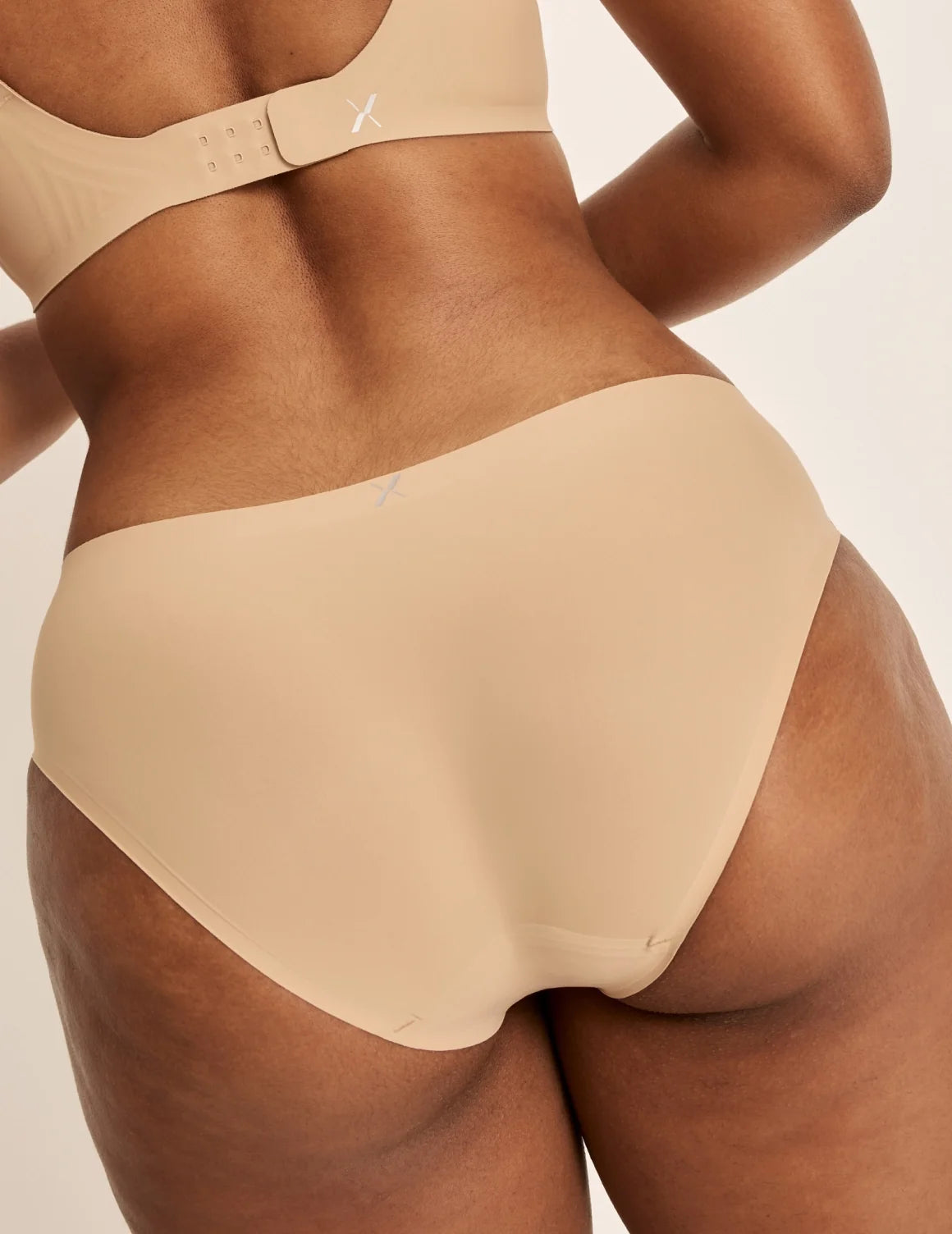 Back view of model wearing the Essential No-Show Bikini highlighting the coverage and smooth fit – Nude Multi – view 11 of 18
