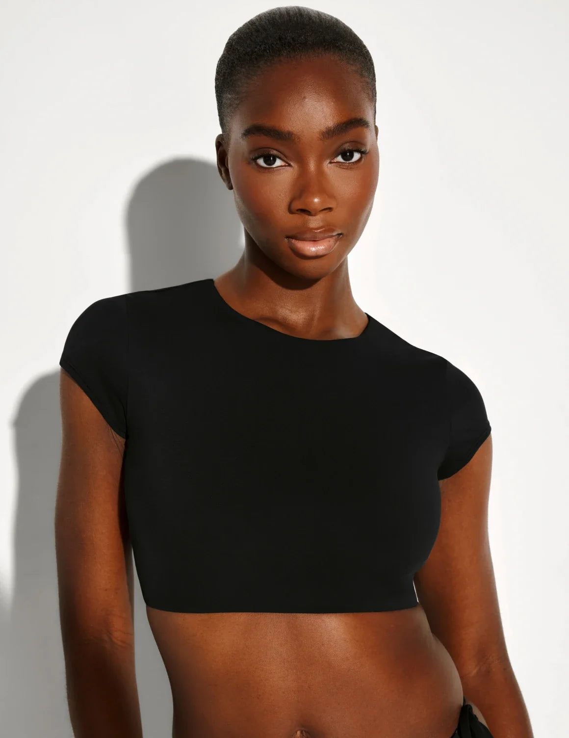 Front view of model wearing the Sculpt Short Sleeve Swim Top, highlighting the neckline, sleeve design, and silhouette – Black – view 1 of 12