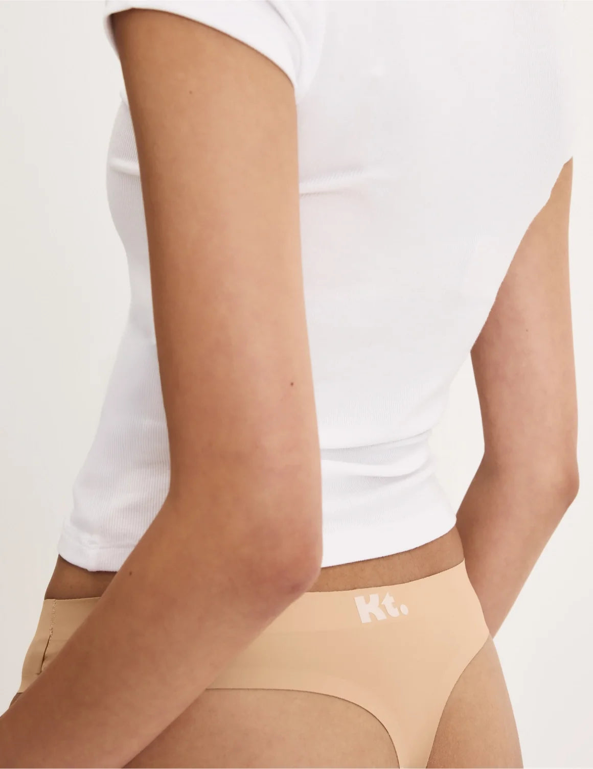Back view of model wearing the Teen Leakproof UltraThin No-Show Thong highlighting the coverage and smooth fit – Warm Sand – view 7 of 34