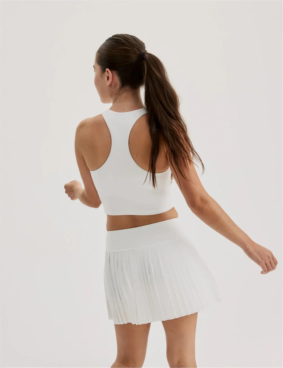Back view of model wearing the Teen First Serve Pleated Skort highlighting the coverage and fit – White – view 6 of 11