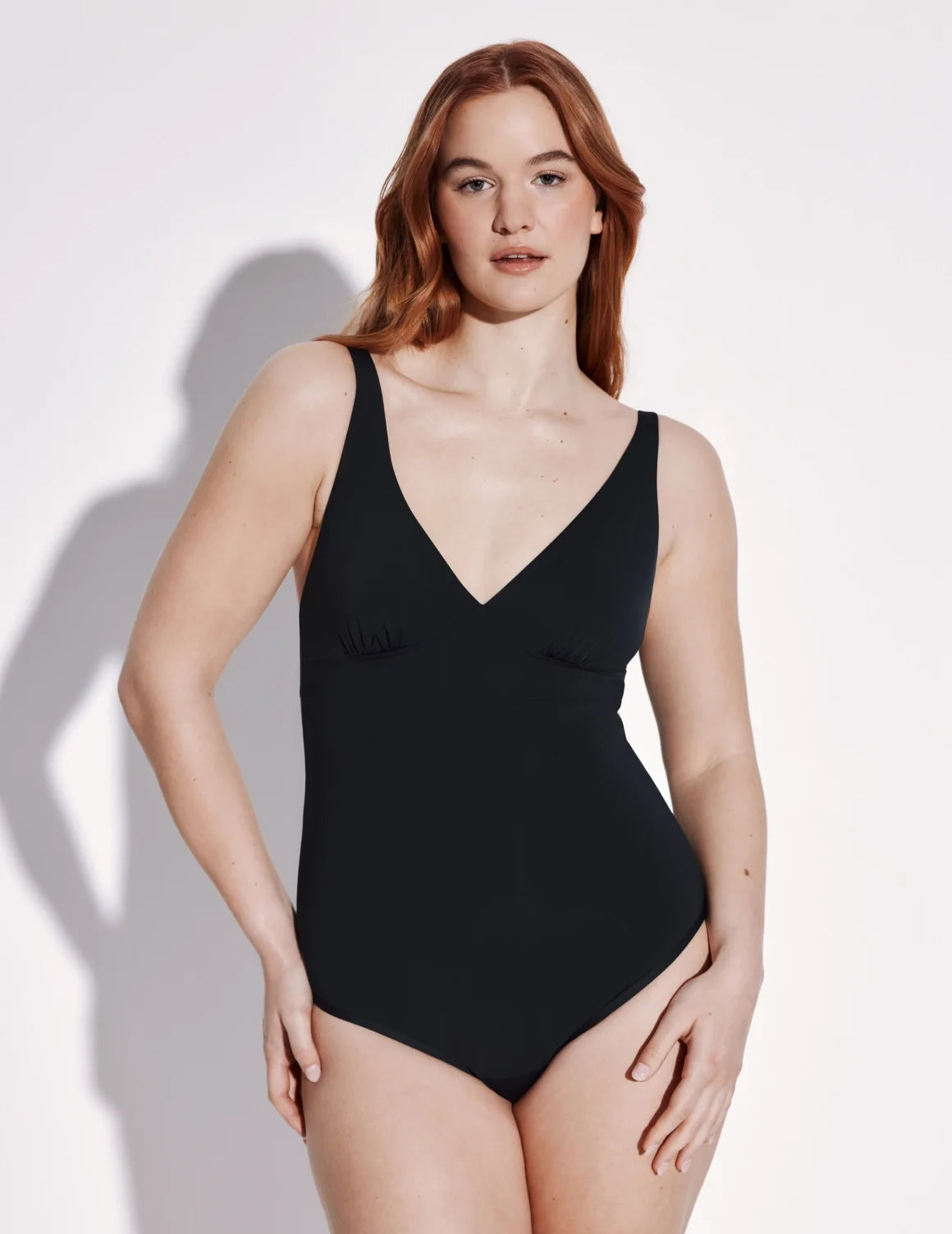 Front view of model wearing the Leakproof Deep V One Piece Swimsuit highlighting the neckline, coverage and fit – Black – view 1 of 4
