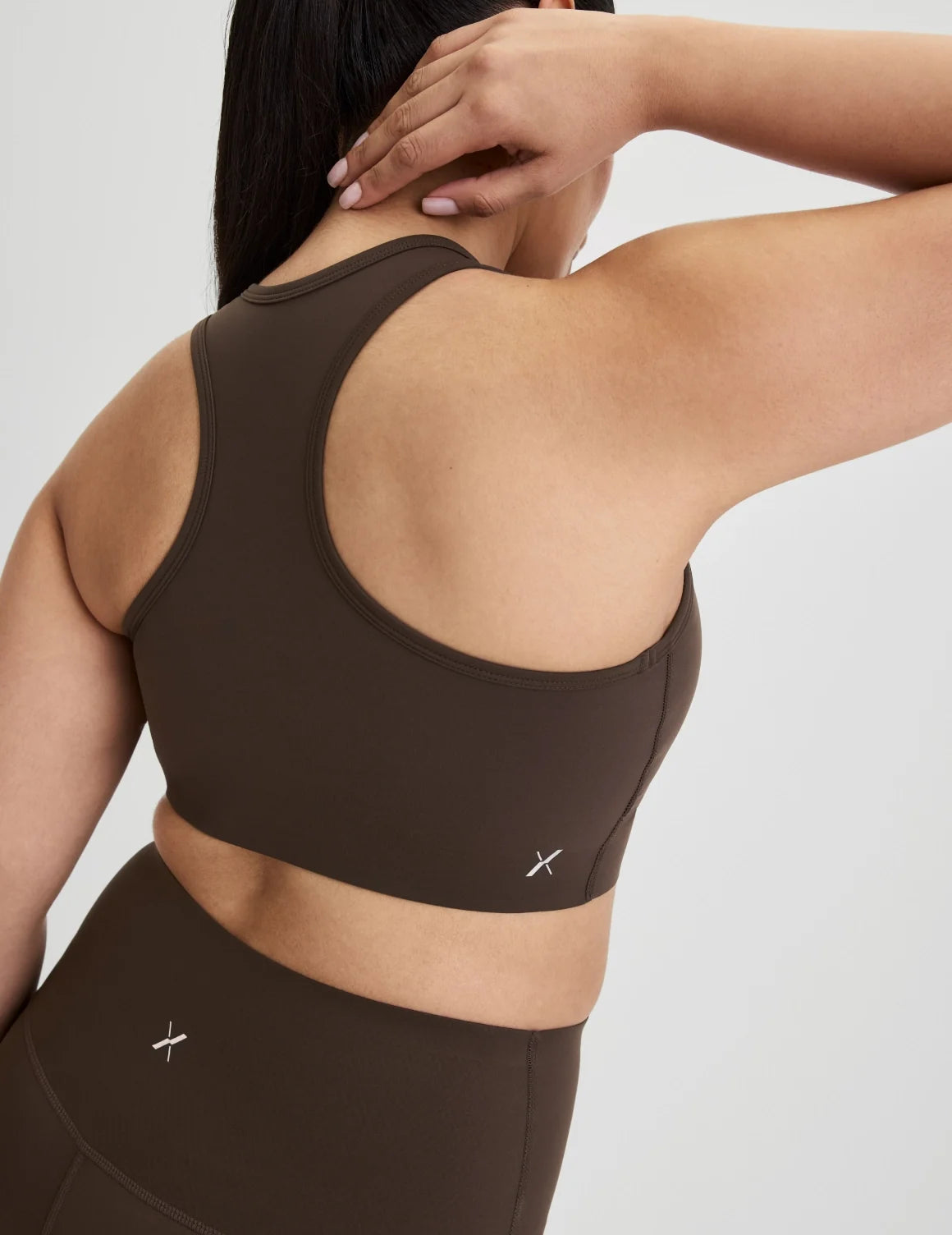 Back view of model wearing the Momenta Racerback Sports Bra, highlighting the neckline, strap design, and silhouette – Espresso – view 7 of 21