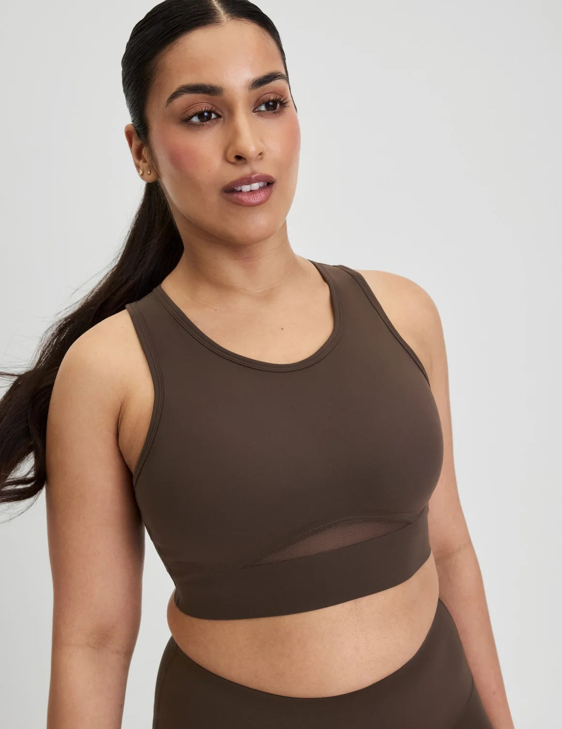 Front view of model wearing the Momenta Racerback Sports Bra, highlighting the neckline, strap design, and silhouette – Espresso – view 8 of 21