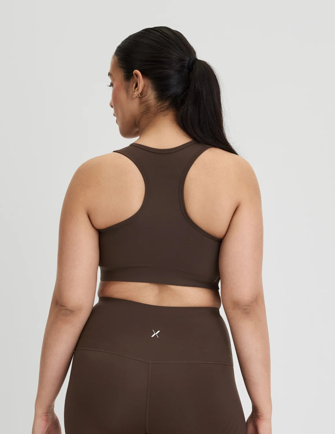 Back view of model wearing the Momenta Racerback Sports Bra, highlighting the neckline, strap design, and silhouette – Espresso – view 9 of 21