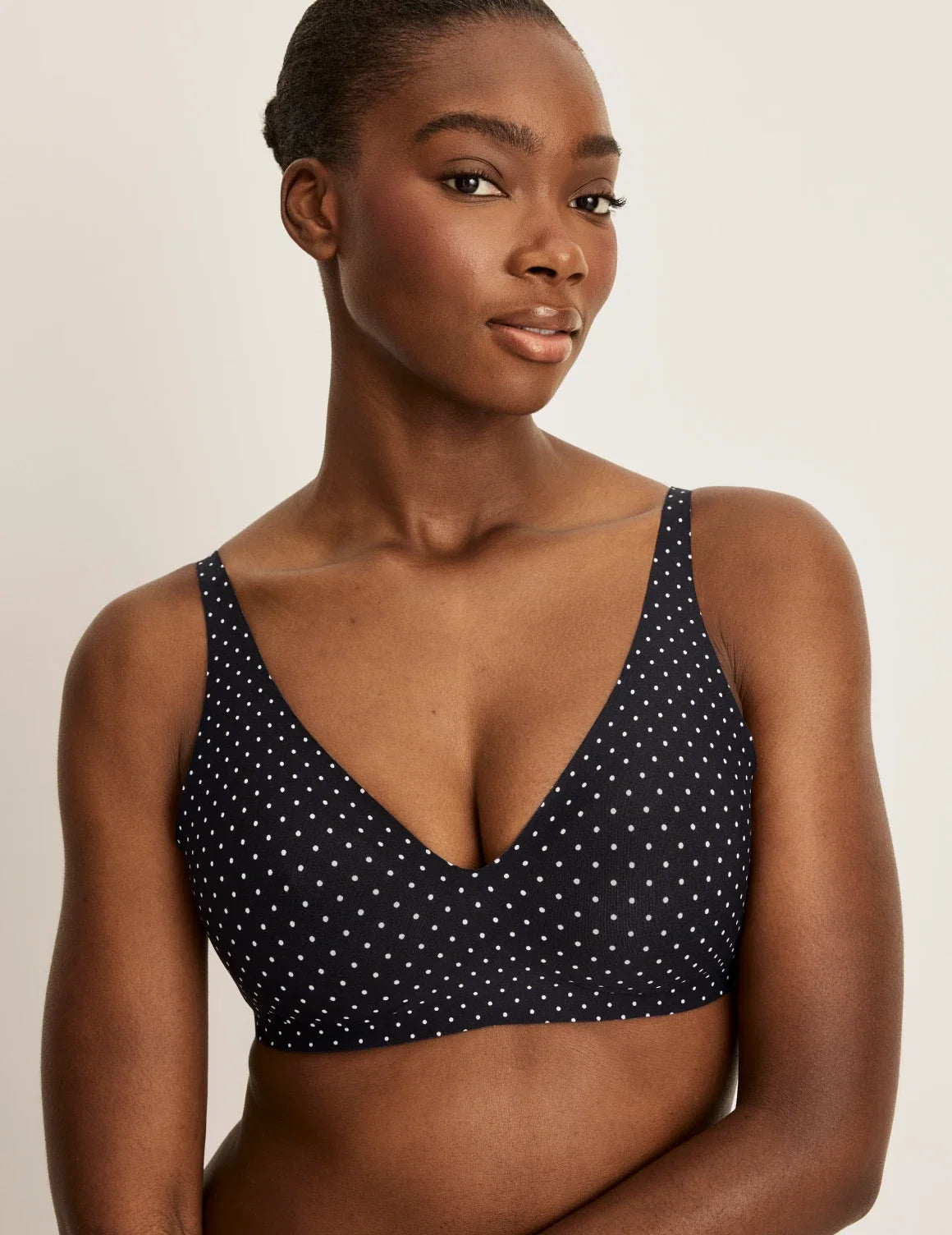 Front view of model wearing the Revolution V-Neck Bra, highlighting the neckline, strap design, and smooth silhouette – Black with White Polka Dot – view 1 of 50
