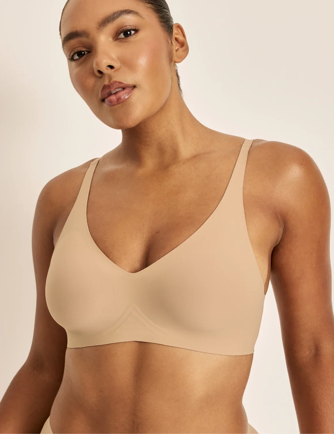 Front view of model wearing the Revolution V-Neck Bra, highlighting the neckline, strap design, and smooth silhouette – Warm Sand – view 7 of 50