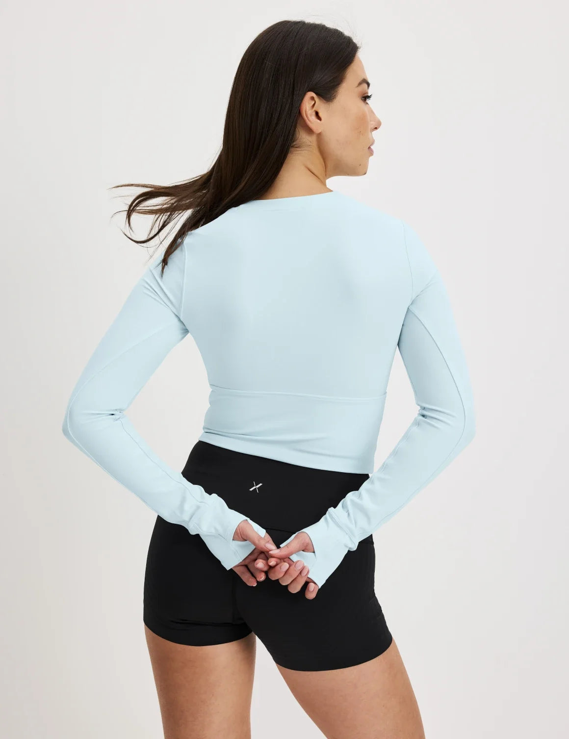 Back view of model wearing the Studio Cutout Bra Top, highlighting the keyhole neckline, flattering design, and silhouette – Blue Light – view 7 of 8